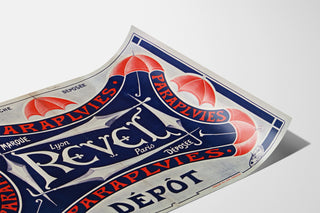 Plakat Paraplyer Revel — Varemærke, Lyon, Paris, vist på et buet ark, perspektivisk set.