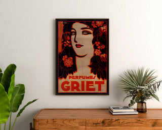Vintage reklameplakat Perfumes Griet, indrammet over en trækommode mellem planter.