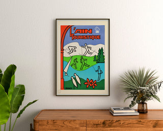 Vintage turistplakat – L’Ain touristique, indrammet over en kommode af træ mellem planter.
