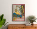 Vintage vinplakat – Au bon vin d’Alsace – Hansi, indrammet over en trækommode mellem planter.