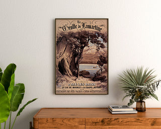 Vintage plakat "Aix-les-Bains, grotte de Lamartine" indrammet over et trækommode mellem planter.