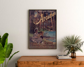 Vintage plakat Arcachon, vintersæson, indrammet over en trækommode mellem planter.