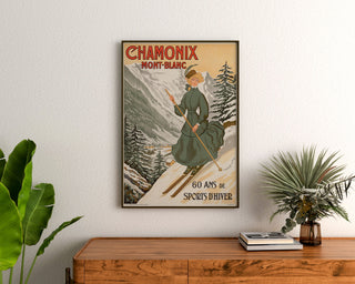Vintageplakat Chamonix, 60 år med vintersport, indrammet over en kommode i træ mellem planter.