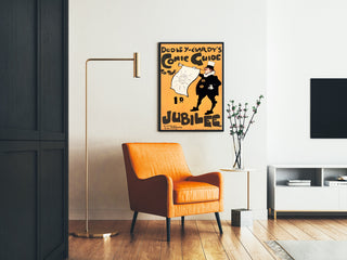 Vintageplakat Dudley Hardy, comic guide, indrammet i en stue med orange lænestol og gulvlampe.