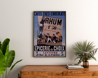 Vintage plakat Épicerie Lefèvre, kaffe og chokolade, indrammet over en kommode i træ, flankeret af planter.