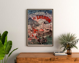 Vintage plakat Luchon, kasino og kurbade, indrammet over en trækommode mellem planter.