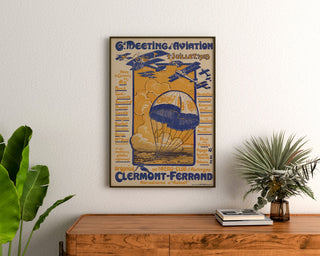 Vintage plakat Flyveopvisning, Clermont-Ferrand, indrammet over en kommode i træ mellem planter.