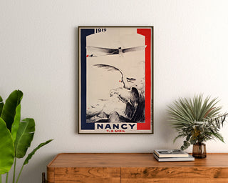 Vintage-plakat Nancy, flyveopvisning, indrammet over en trækommode mellem planter.