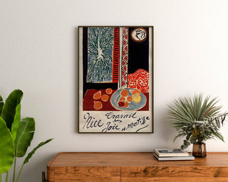 Vintageplakat Nice, travail et joie, indrammet over en trækommode mellem planter.