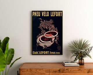Vintage plakat Pneus vélo Lefort, indrammet over en trækommode mellem planter.