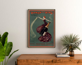 Vintageplakat Woman and Wine, Princess’s Theatre, indrammet over en trækommode mellem planter.